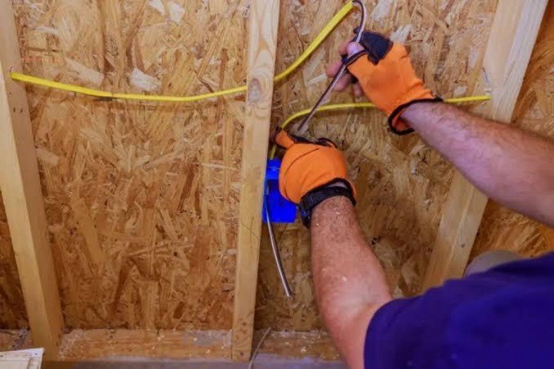 Electrician completing rough-in wiring before drywall