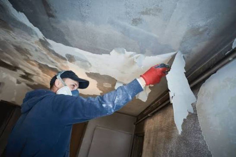 Technician cleaning soot and smoke residue from a wall
